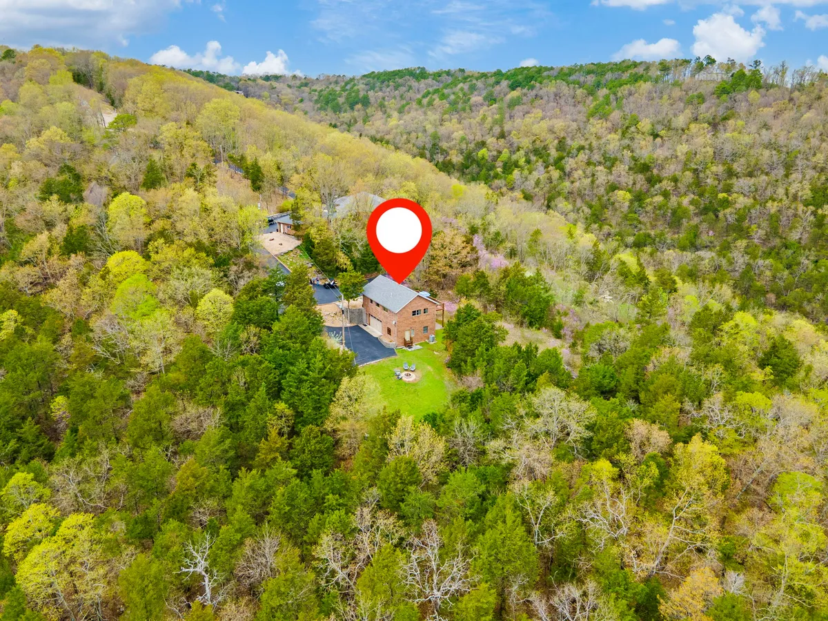 The exterior of the house with a spacious green lawn, outdoor seating area, and surrounding trees. The inviting yard space is suited for gatherings, evening bonfires, and relaxing after a day of adventure.
